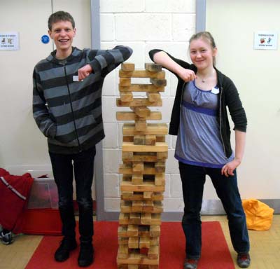 Two young people leaning on a tower of wooden bricks